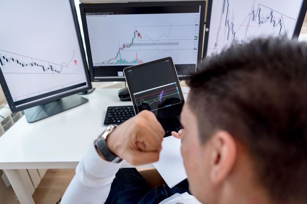 a man monitoring graphs on multiple screens