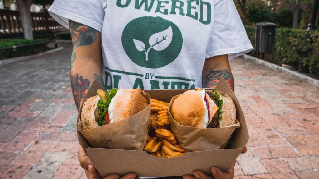 a person holding a vegan food on a takeout box